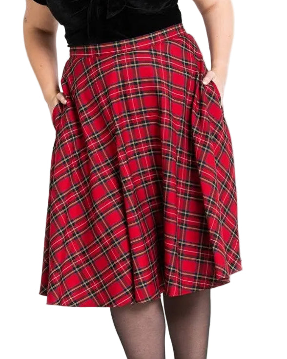Person wearing a black top and red plaid skirt on a white background