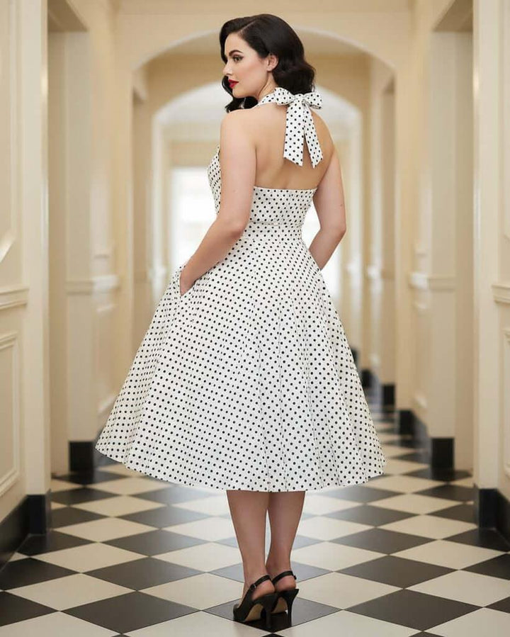 Close-up of white polka dot halter dress showing wrap bust, fitted waist and flared skirt
